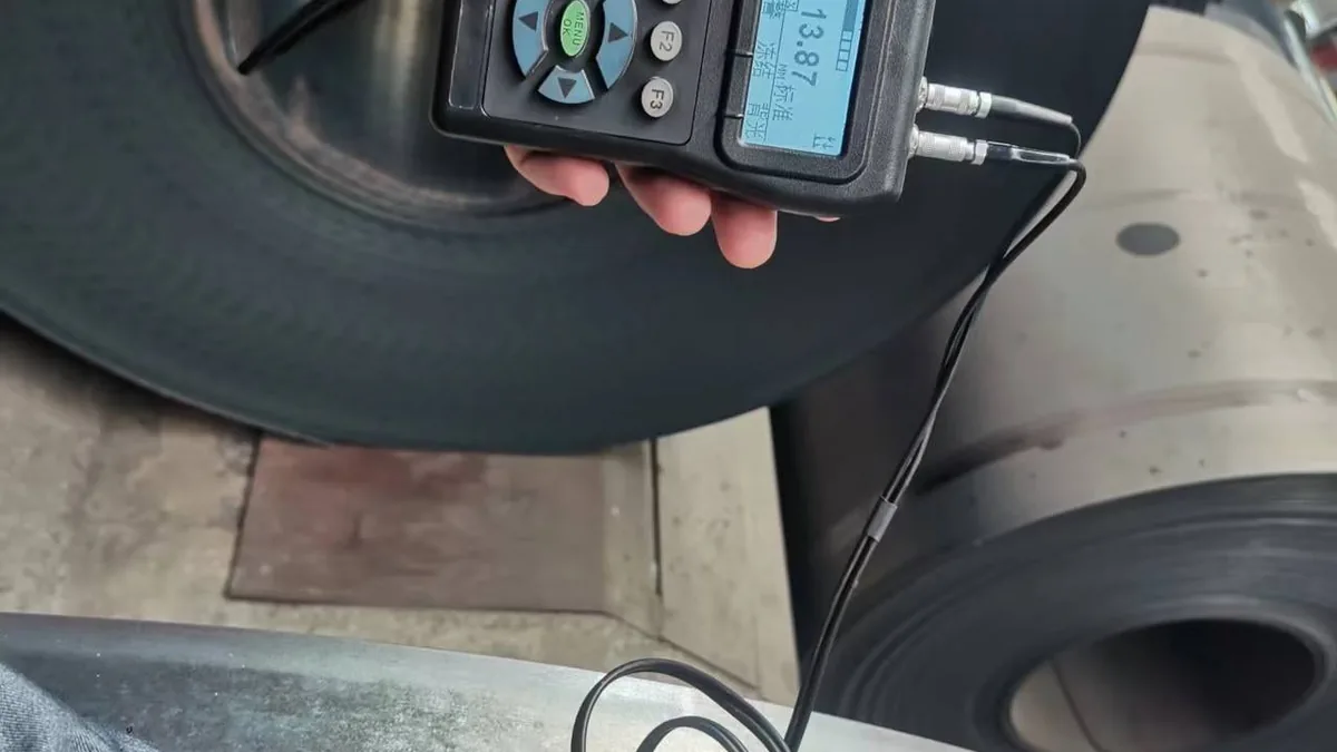 Técnico midiendo el espesor de una bobina de acero con un micrómetro calibrado
